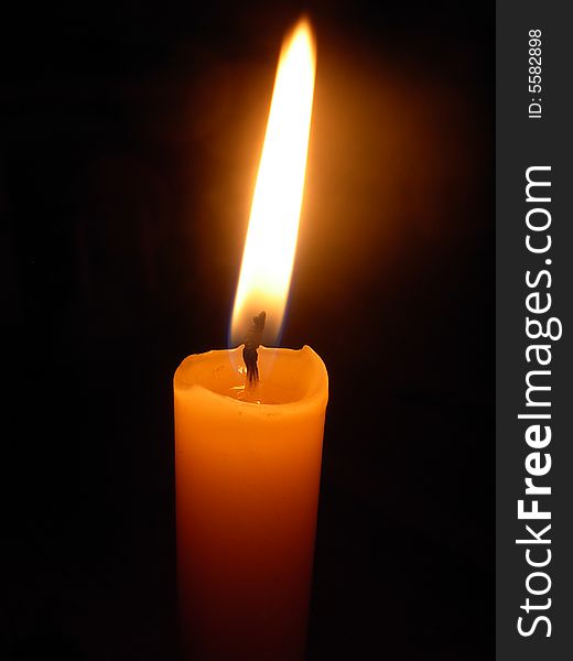 Macro close up of a candle with elongated flame with dark background. Macro close up of a candle with elongated flame with dark background
