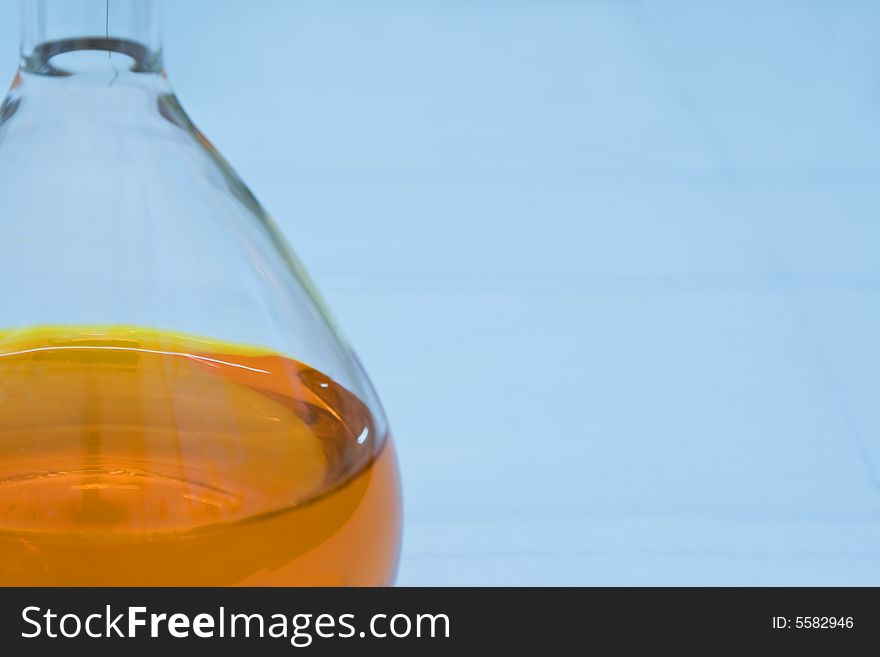 Detail image of a lab flask containing an orange solution (soft focus). Detail image of a lab flask containing an orange solution (soft focus)