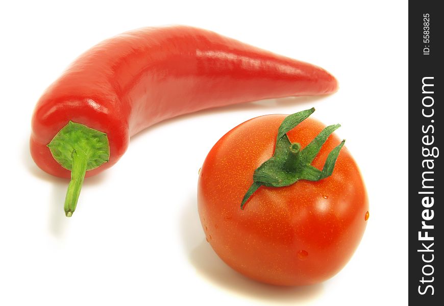 A fresh tomato and a ripe chili pepper isolated on white background. A fresh tomato and a ripe chili pepper isolated on white background