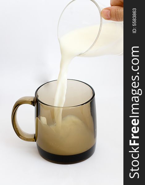 Pouring creamy milk in a black glass. Pouring creamy milk in a black glass