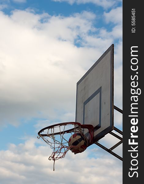 Striped ball inside the hoop against the cloudy sky. Striped ball inside the hoop against the cloudy sky