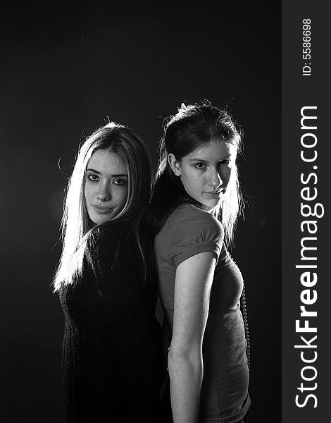 Two teenage girls standing back to, in black and white. Two teenage girls standing back to, in black and white