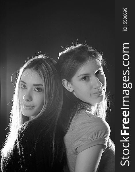 Black and white portrait of 2 sisters standing back to back. Black and white portrait of 2 sisters standing back to back