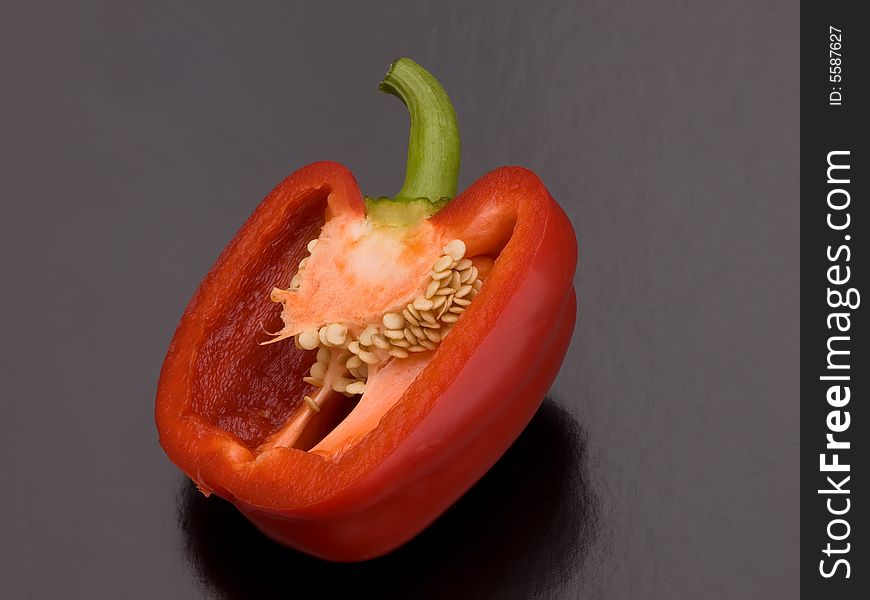 A red pepper cut in half on a black background. A red pepper cut in half on a black background.