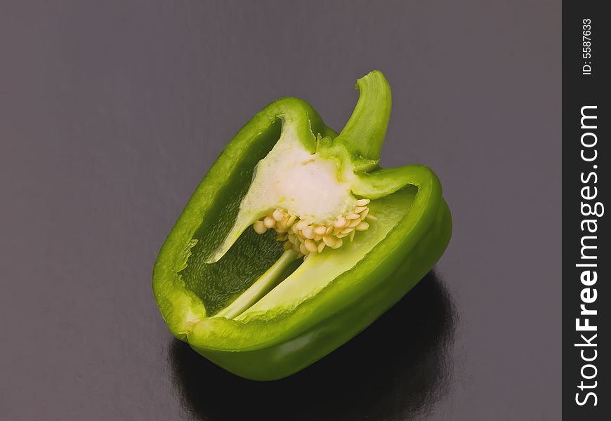 A green pepper cut in half on a black background. A green pepper cut in half on a black background.