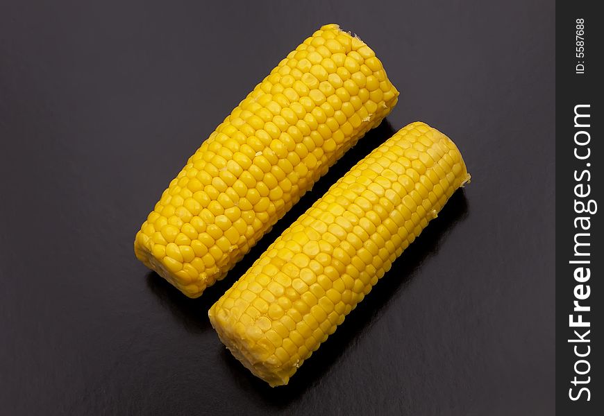 Two sweet-corns on the cob side by side with a black background. Two sweet-corns on the cob side by side with a black background.