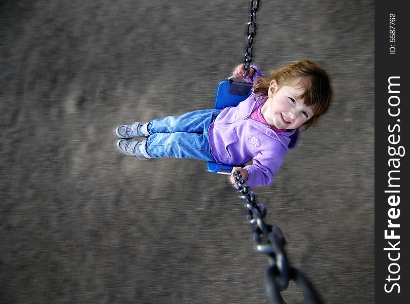 Little girl playing on merri-go-round at a park. Little girl playing on merri-go-round at a park