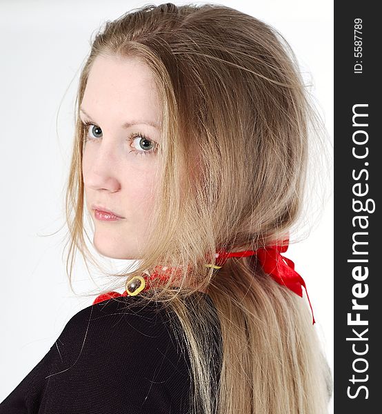 Girl with long blond hair with red ribbon wearing black dress looks backward. Girl with long blond hair with red ribbon wearing black dress looks backward