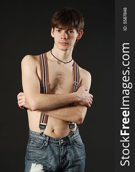 Young cute man with naked torso wearing jeans and braces. Young cute man with naked torso wearing jeans and braces