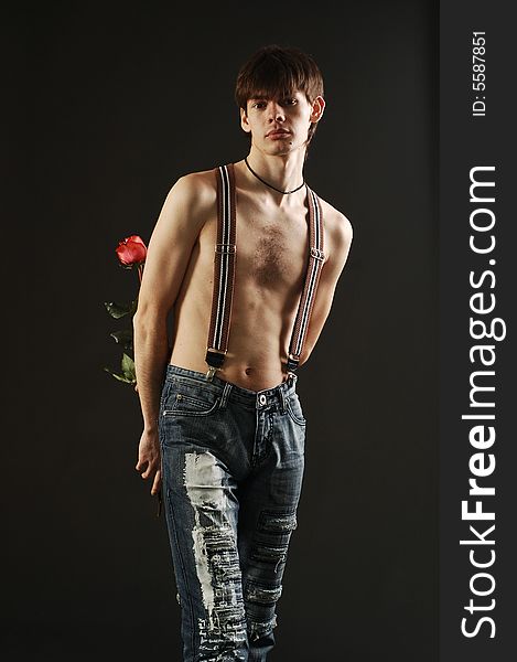 short haired man with a nude torso wearing jeans hides a red rose behind his back. short haired man with a nude torso wearing jeans hides a red rose behind his back