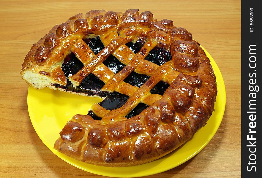 Fresh sweet pie with bilberry on a yellow plate. Fresh sweet pie with bilberry on a yellow plate