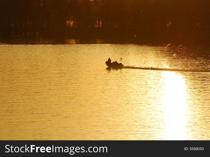 A powerboat heads home after a day of fishing.  As they travel their wake breaks the reflection of the setting sun. A powerboat heads home after a day of fishing.  As they travel their wake breaks the reflection of the setting sun.