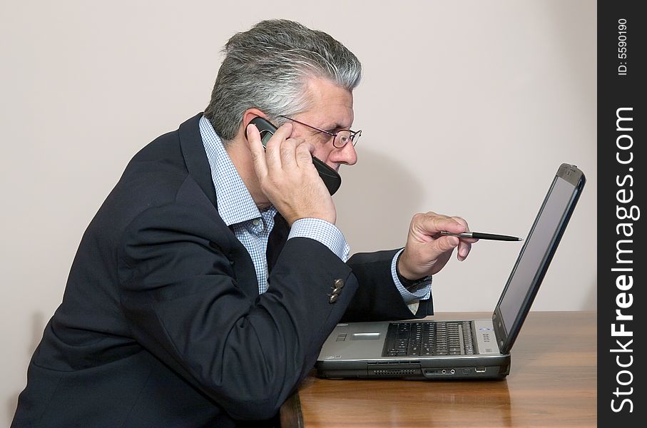 A businessman working in his study with a computer. A businessman working in his study with a computer
