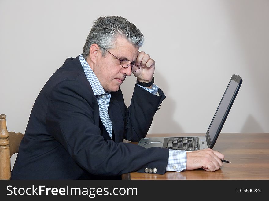 A businessman working in his study with a computer. A businessman working in his study with a computer