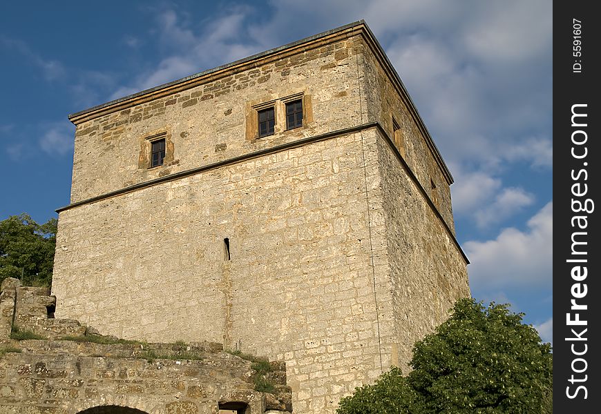 Stone tower of an ancient castle in front of blue sky with white clouds. Stone tower of an ancient castle in front of blue sky with white clouds