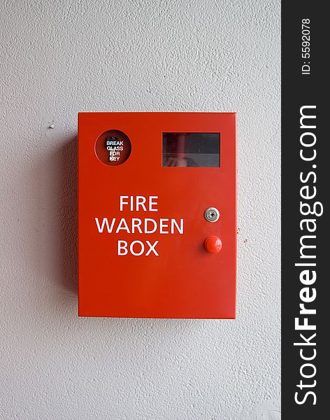 A red fire warden box hangs on a white wall