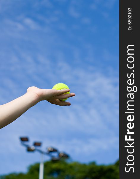 A hand holding a fresh green tennis ball in the air. A hand holding a fresh green tennis ball in the air.