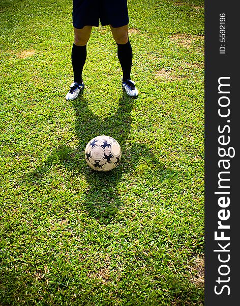 The shadow of a asian football player together with a football on green grass. The shadow of a asian football player together with a football on green grass