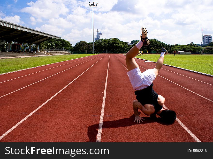 An asian male athlete in the red raceway with a headstand gesture to show his power and skills, muscle.