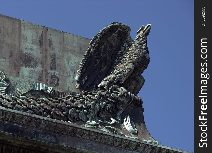 Detail of an ancient building: a stone eagle with a blue sky as background