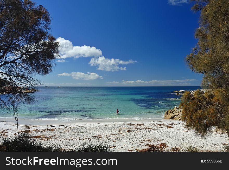 A lone fisherman, standing waist-deep in water, casts his line into a tropical bay. Space for copy in the sky. A lone fisherman, standing waist-deep in water, casts his line into a tropical bay. Space for copy in the sky.