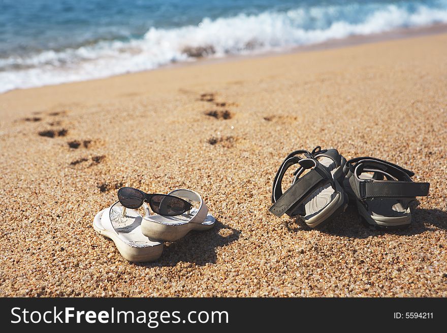 A photo of two pairs of beach shoes at the seaside