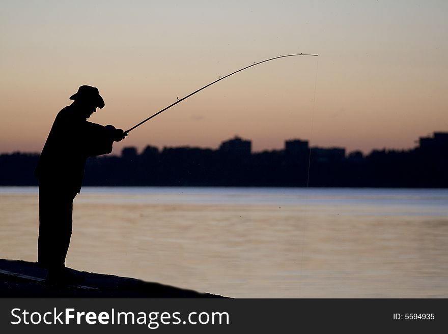 Siluett of the fisherman near the river when the Sun goes down. Siluett of the fisherman near the river when the Sun goes down