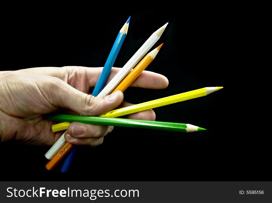 hand with pencils on a black background. hand with pencils on a black background