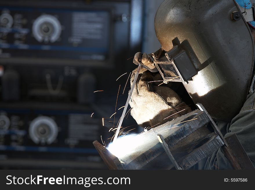 A welder working at shipyard during day shift. A welder working at shipyard during day shift
