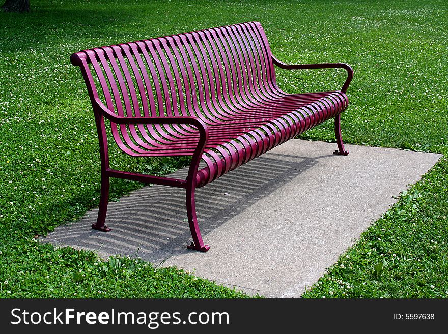 A red bench sits empty and waiting in a park. A red bench sits empty and waiting in a park.