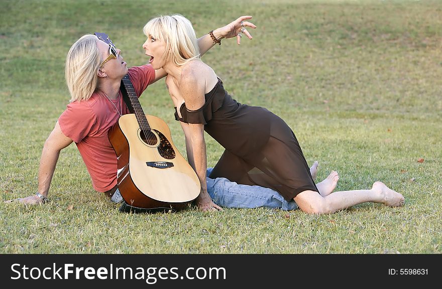 Hip adult couple with a guitar outside on grass. Hip adult couple with a guitar outside on grass