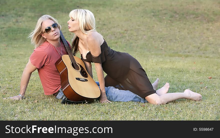 Hip adult couple with a guitar outside on grass. Hip adult couple with a guitar outside on grass