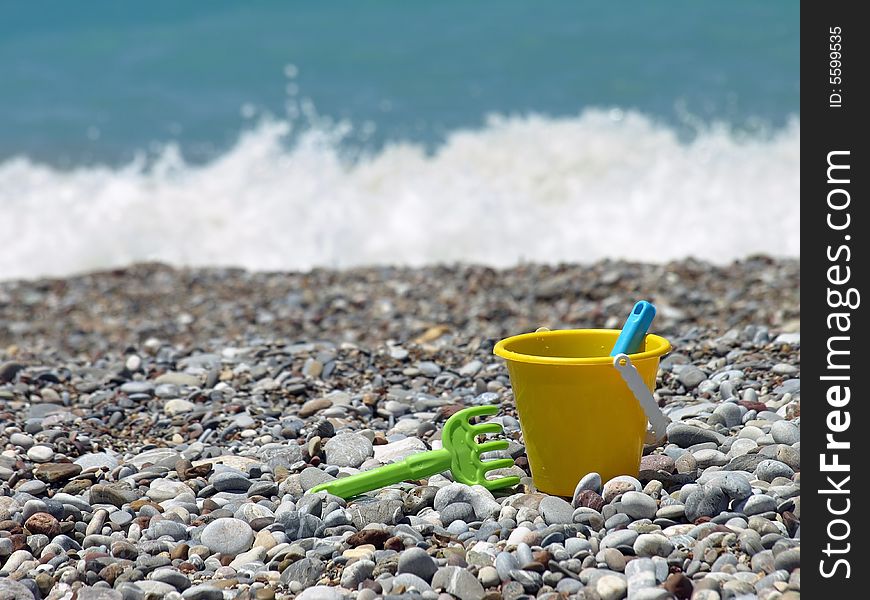 Yellow bucket and green rake on a beach. Yellow bucket and green rake on a beach.