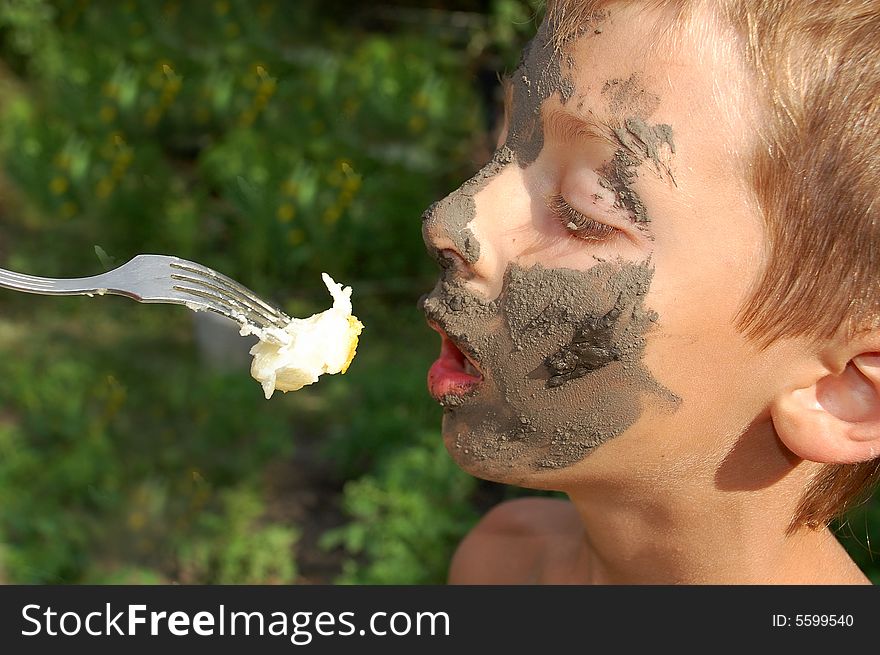 Muddy faced boy having a fast snack with the help of his mother while the short break in the game. Muddy faced boy having a fast snack with the help of his mother while the short break in the game