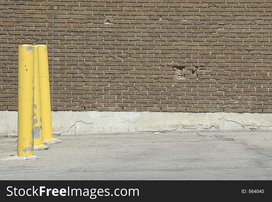 Yellow parking poles in a parking lot against a brick wall. Yellow parking poles in a parking lot against a brick wall.