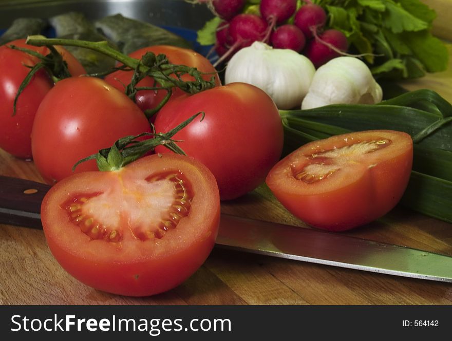 Vine tomatoes at cutting board, vegetables at background. Vine tomatoes at cutting board, vegetables at background