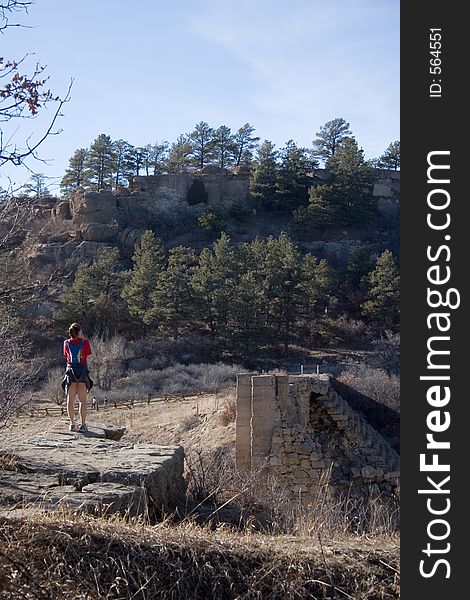 A hiker seems lost in thought as she stands on one end of a broken dam, looking at the other side, in Castlewood Canyon of central Colorado. A hiker seems lost in thought as she stands on one end of a broken dam, looking at the other side, in Castlewood Canyon of central Colorado.