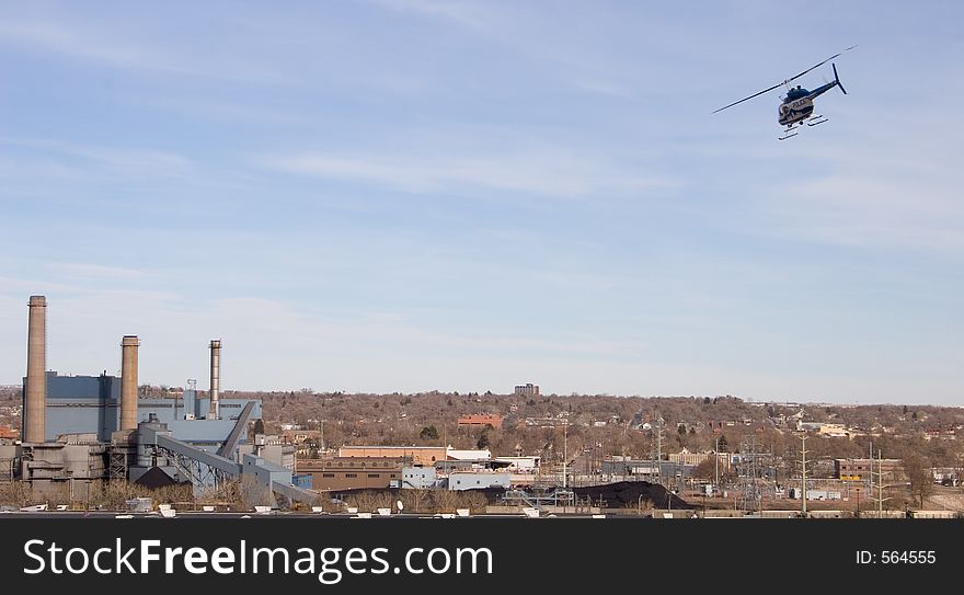 A blue and white police helicopter patrols over the power plant in downtown Colorado Springs. A blue and white police helicopter patrols over the power plant in downtown Colorado Springs