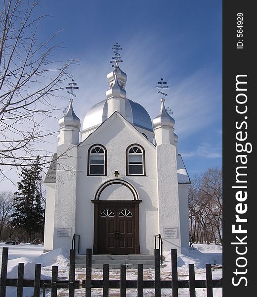 This image depicts a small church with silver domes in the winter season.