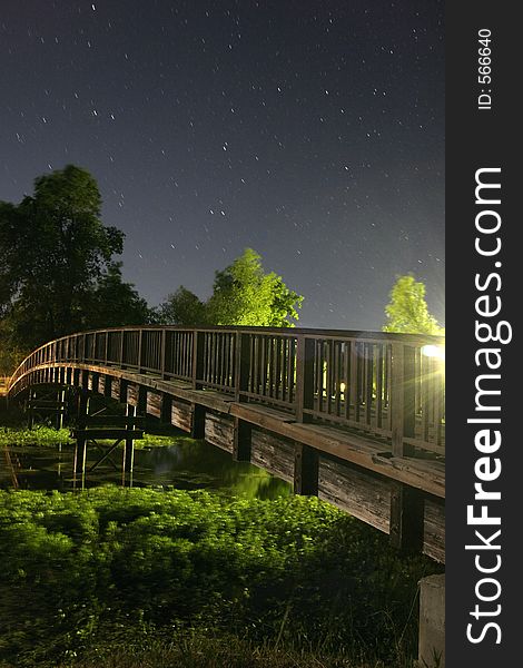 A wooden brige that spans a creek at night. A wooden brige that spans a creek at night.