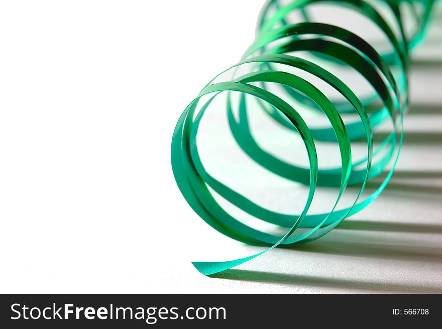 A curly green ribbon on white ground with shadows