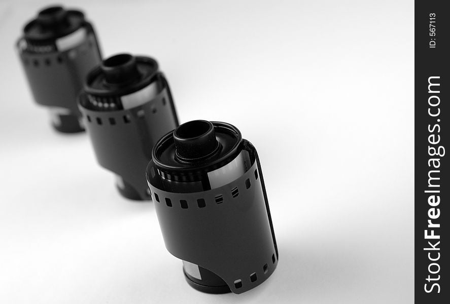 Black & White Image of unexposed 35mm film rolls. Three in a line, shallow depth of field with focus on first roll.