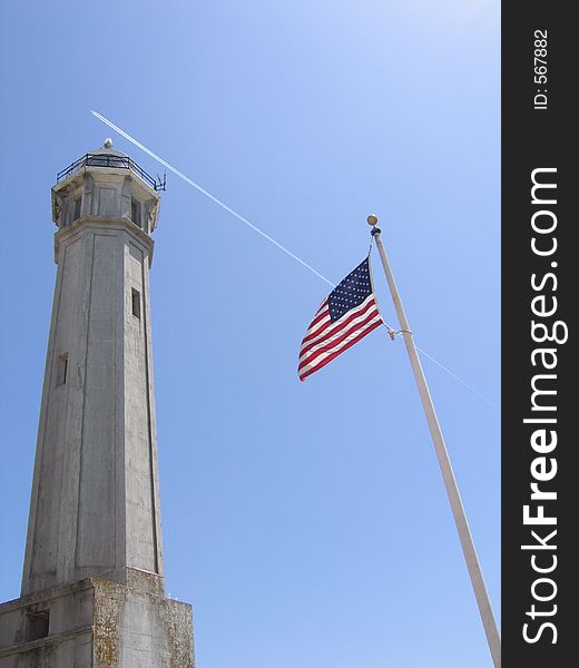 Alcatraz lighthouse and American flag on a pole.