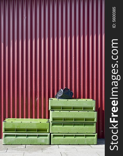 Some green fish boxes at a red wall