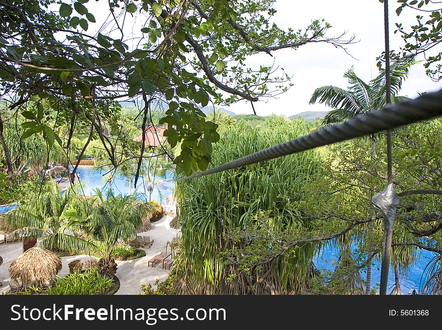 A zip line over a tropical resort swimming pool. A zip line over a tropical resort swimming pool