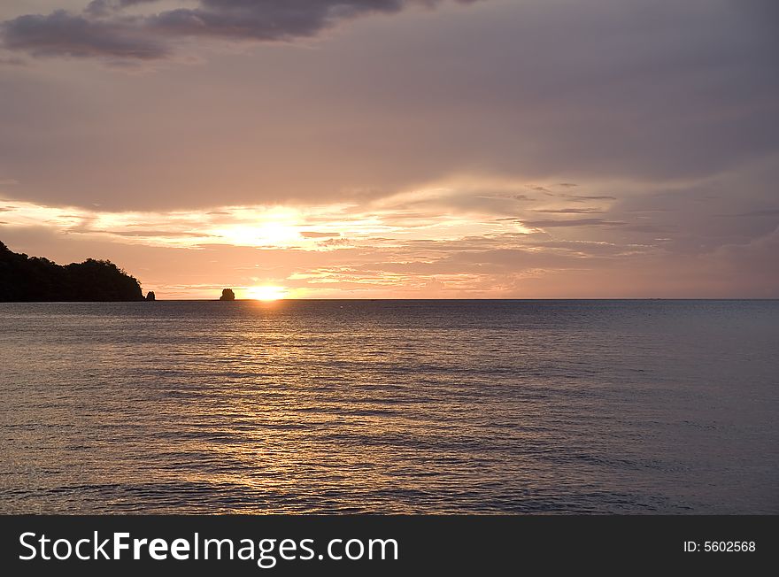 An orange and pink sunset by the rocks off the coast of Costa Rica