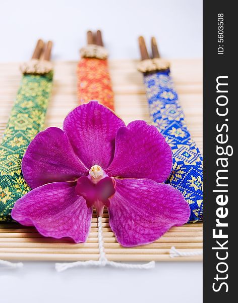 3 Pairs of chopsticks and an orchid on wooden placemat