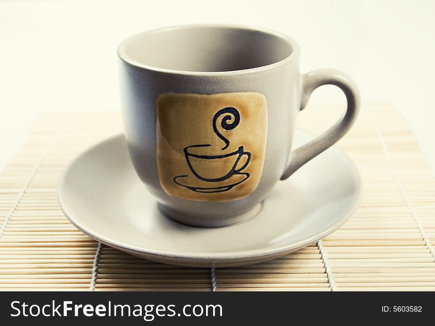 Coffee cup and saucer on top of wooden placemat