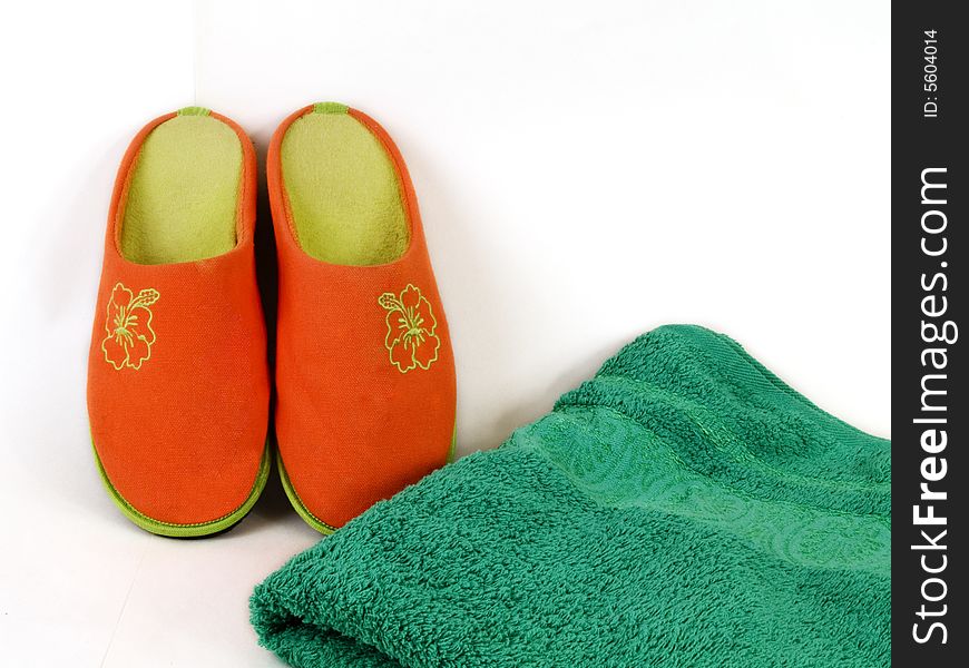 Orange carpet slippers and green folded towel. Orange carpet slippers and green folded towel