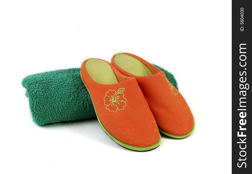 Orange carpet slippers and green folded towel. Orange carpet slippers and green folded towel